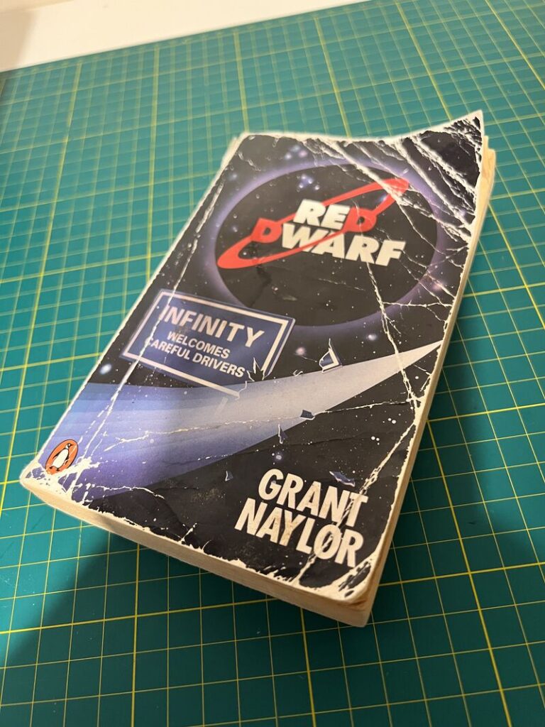 A battered copy of the book Red Dwarf Infinity Welcomes Careful Drivers