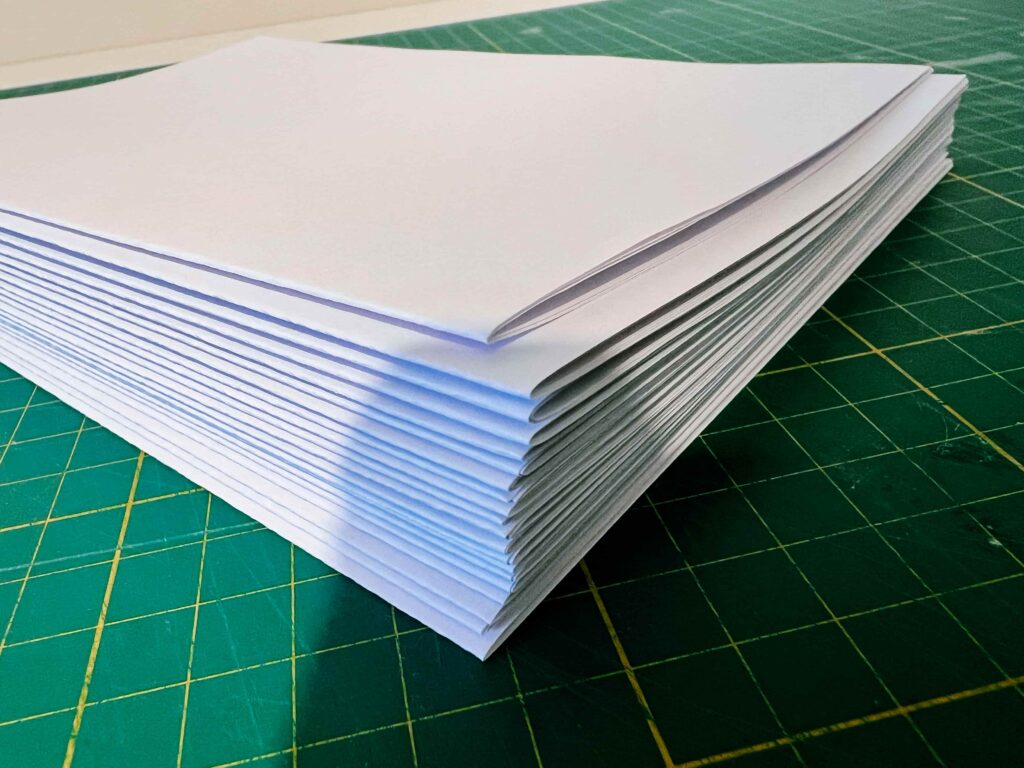 A pile of papers all ready to be sewn into a book